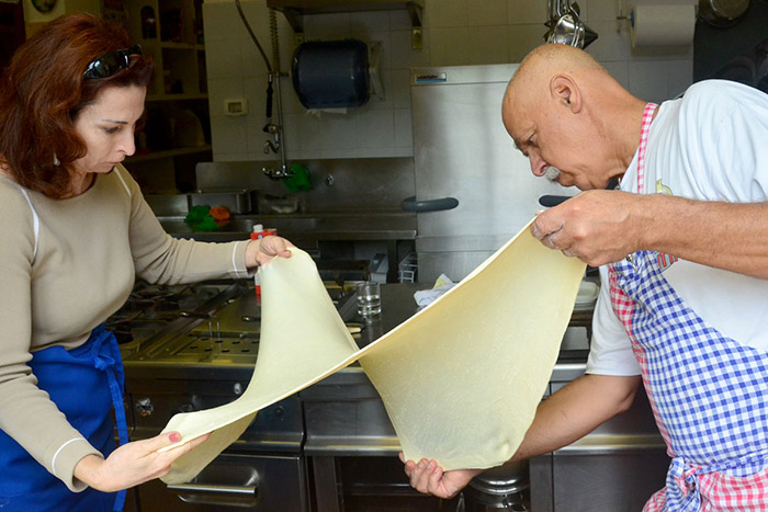 Cuochi che lavorano una sfoglia fresca per la pasta