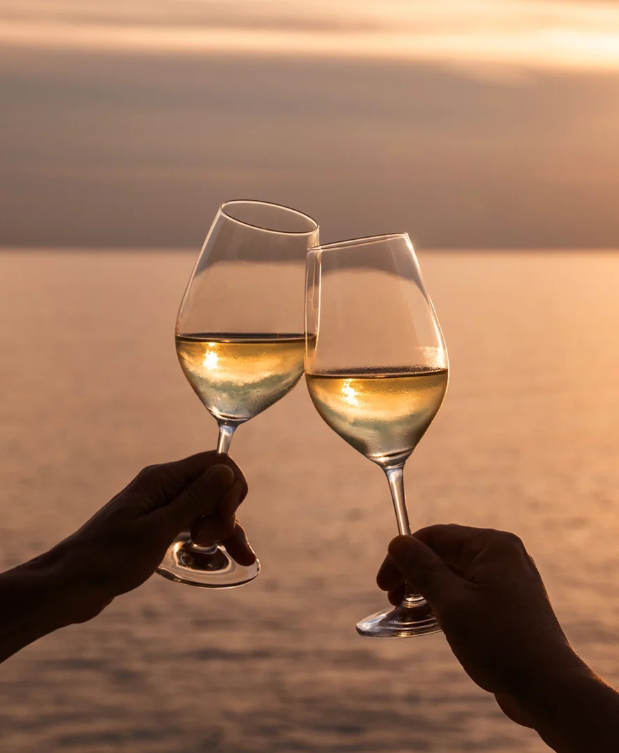 Brindisi con vino bianco al tramonto sul mare