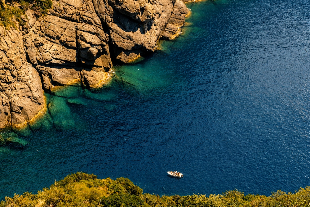 Boat in a bay among the cliffs of the Portofino Promontory