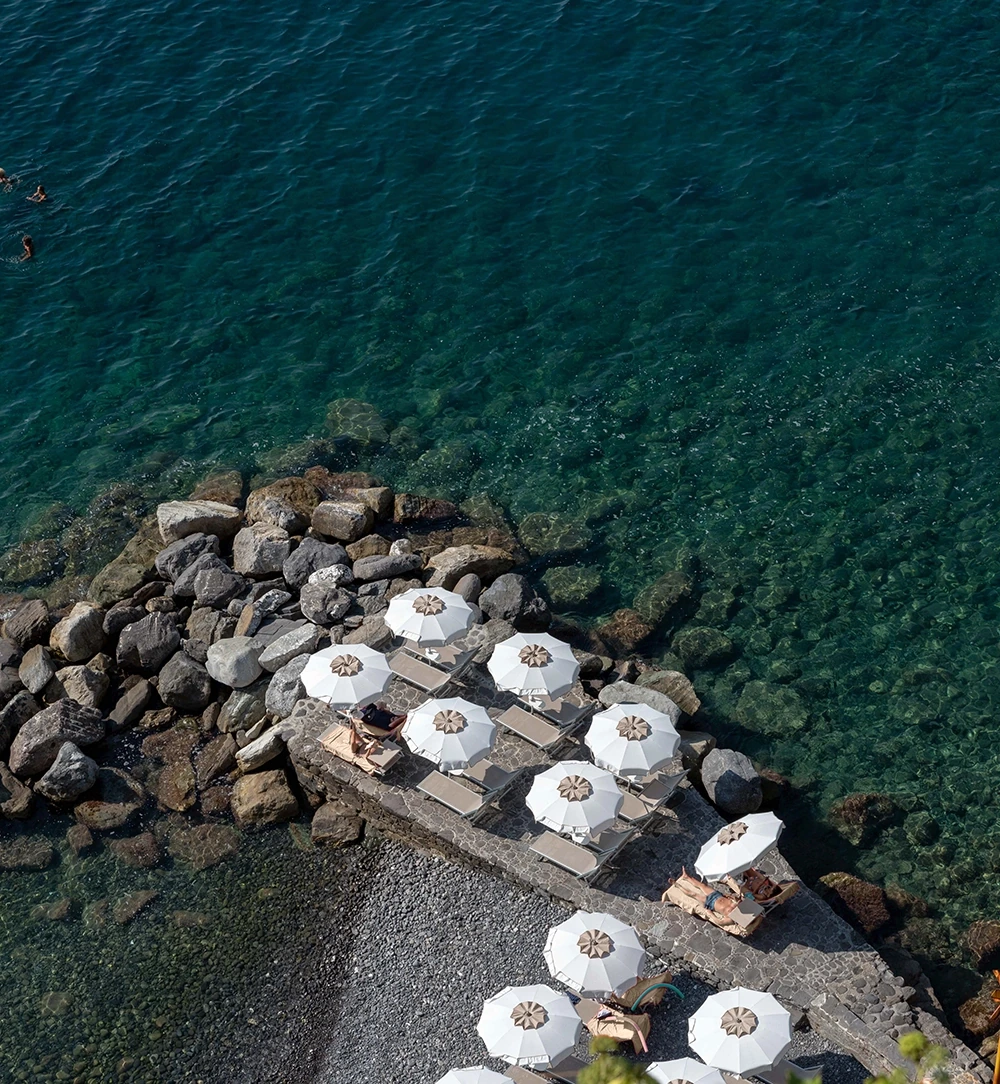 Ombrelloni bianchi della spiaggia privata sugli scogli di Camogli
